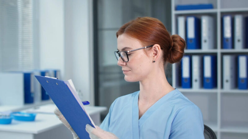 The nurse is holding patient records in her hands