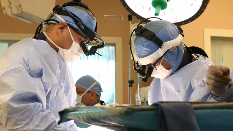 Surgeons in Blue Scrubs and Head-Mounted Lights Perform a Surgical Procedure in An Operating Room