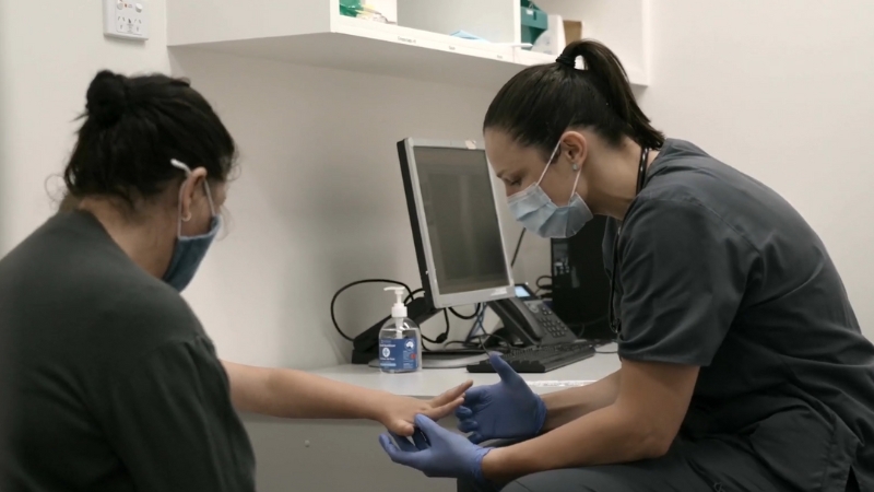 A Nurse Examines a Patient's Hand in A Clinical Setting