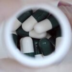 Close-Up of Green and White Capsules in A Bottle, Symbolizing Preparation for A Career in Pharmacy