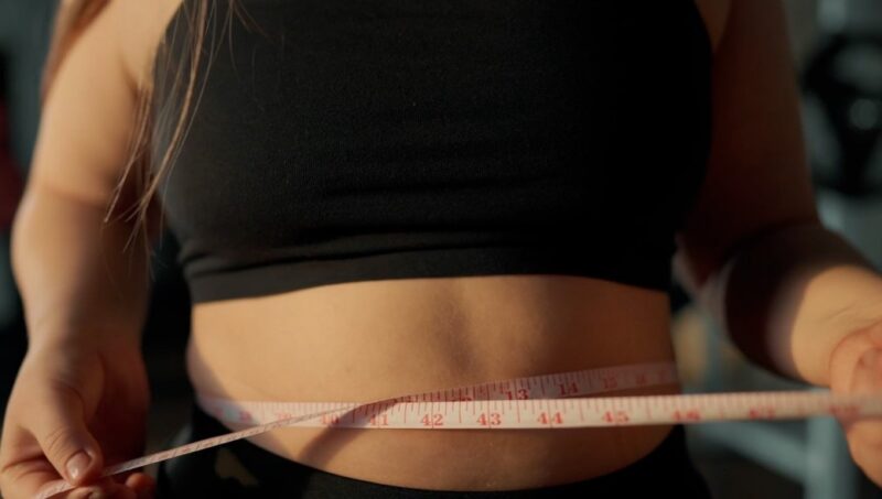 Woman holding a measuring tape around their waist