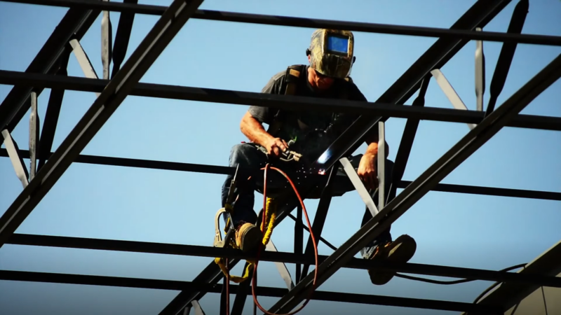 A Steelworker Welding High Above the Ground on A Metal Structure