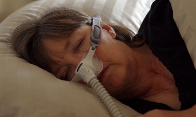 Woman sleeping in bed with sleep apnea