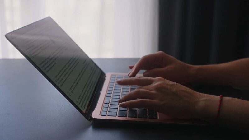 A close-up of hands typing on a laptop keyboard, with a document visible on the screen