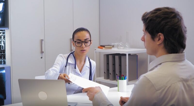 A doctor presents medical documents to a patient, highlighting a professional consultation