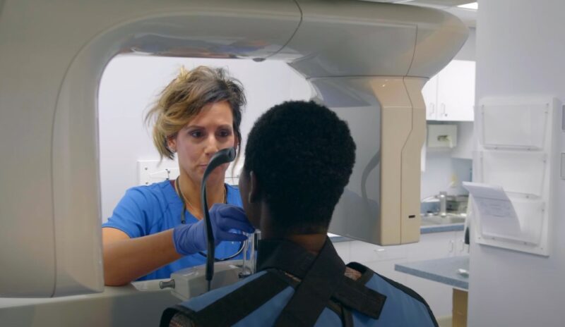 Dental X-ray procedure in progress. A patient is positioned for a dental X-ray